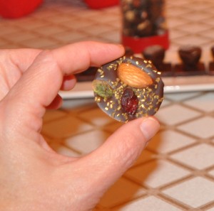 A chocolate mendiant with pistachio, almond and cranberry, sprinkled with gold sugar.